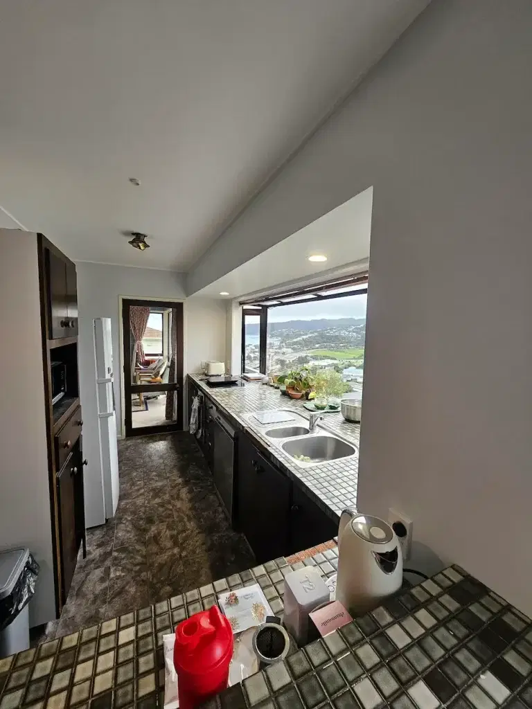 Interior Painting Porirua: Expert Interior House Painters 2 Freshly painted galley kitchen with light gray walls, dark cabinetry, tiled countertops, and a large picture window